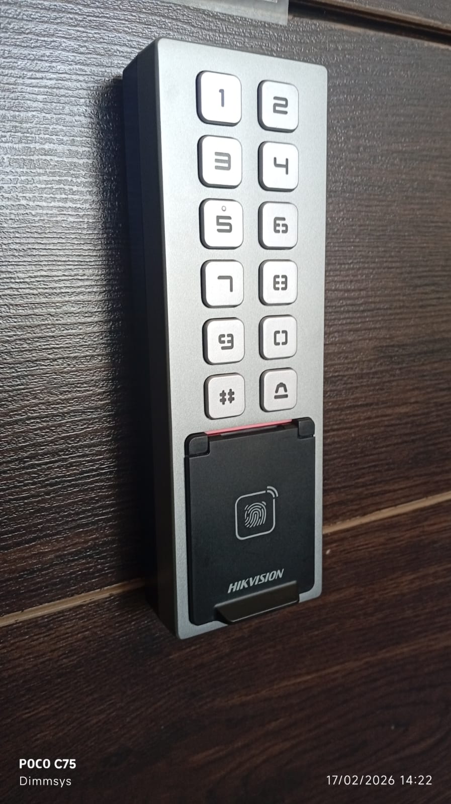 Lector Hikvision con teclado y sensor de huella montado en una puerta