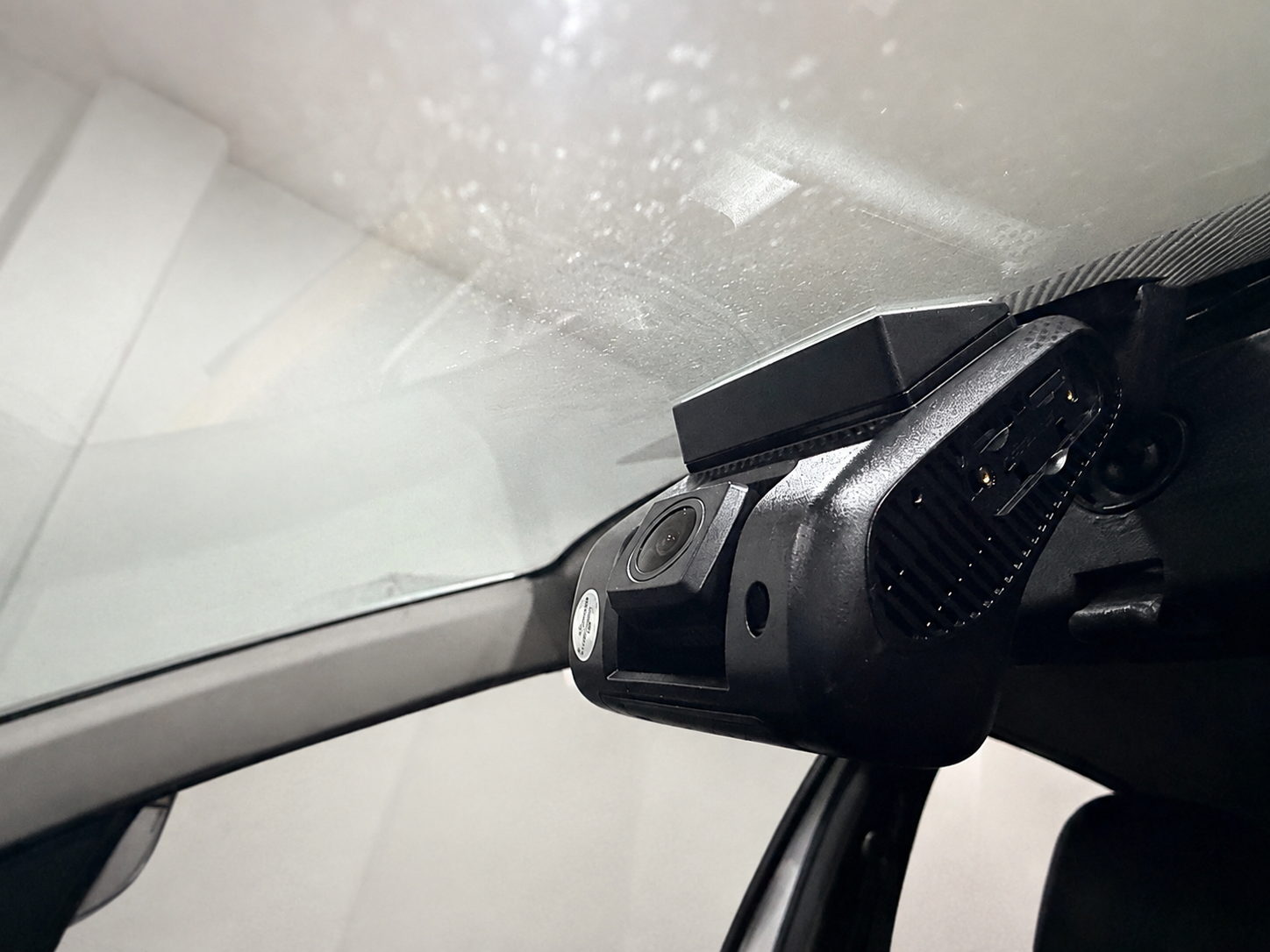 Dashcam instalada en el parabrisas de un vehículo; fondo de la fotografía retocado